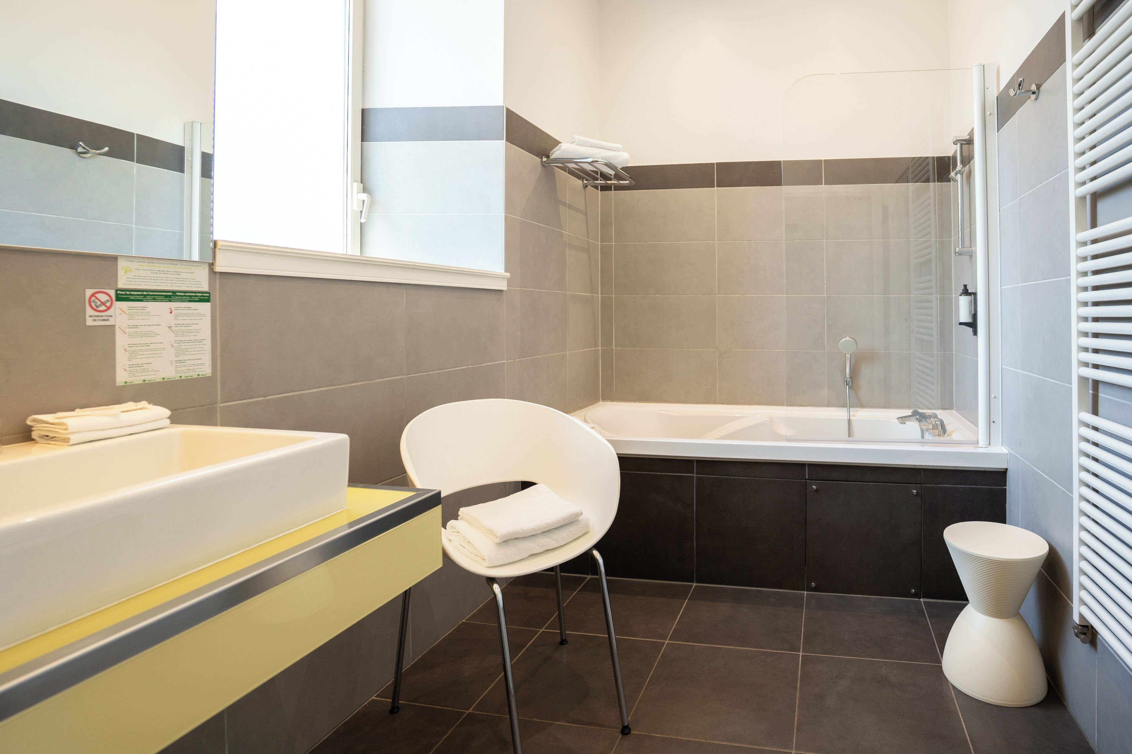 A modern bathroom with a bathtub, a white chair, and a toilet.