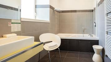 A modern bathroom with a bathtub, a white chair, and a toilet.
