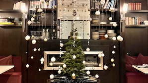 A cozy room with a Christmas tree, bookshelves, and hanging ornaments.