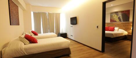 A modern hotel room with two beds, a flat-screen TV, and a large mirror reflecting the room.