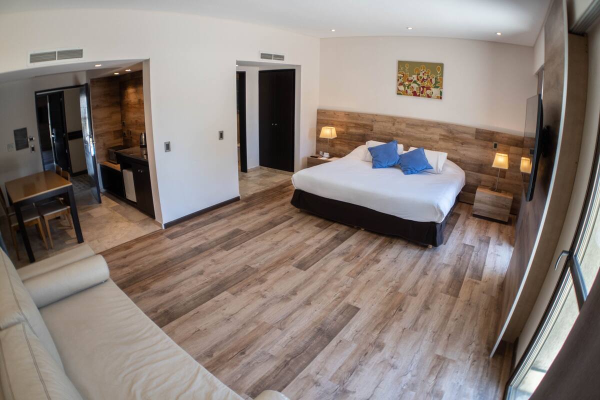 Ein modernes Hotelzimmer mit einem großen Bett, einem Schreibtisch und einem separaten Essbereich.