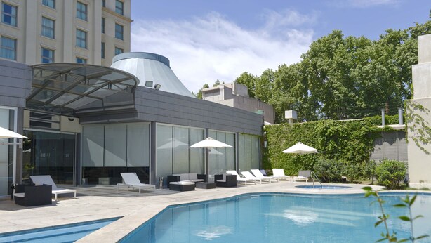 A modern hotel with a swimming pool, lounge chairs, and umbrellas. - Mod Hotels Mendoza (Mendoza)