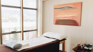 Enjoy a city view from the comfort of this cozy room, featuring a single bed, a small table with a kettle, and a beautiful painting.