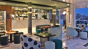 Zona de bar moderna con asientos, exhibición de vinos y vistas a la ciudad.