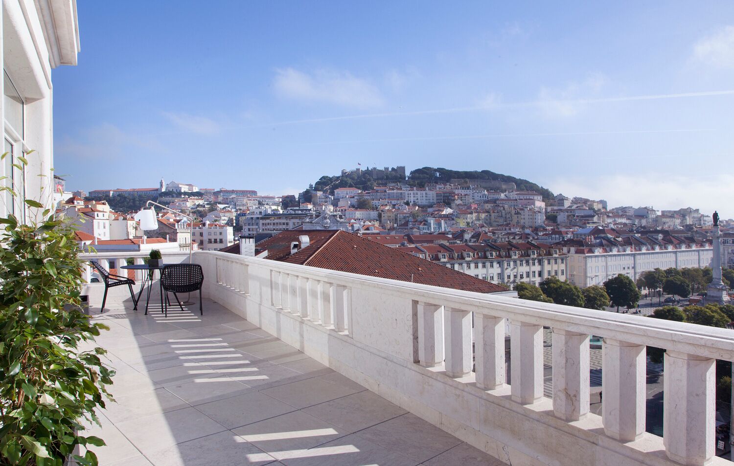 Un balcon offrant une vue sur le paysage urbain, avec notamment un sommet de colline et des bâtiments.