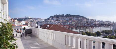 Un balcon offrant une vue sur le paysage urbain, avec notamment un sommet de colline et des bâtiments.