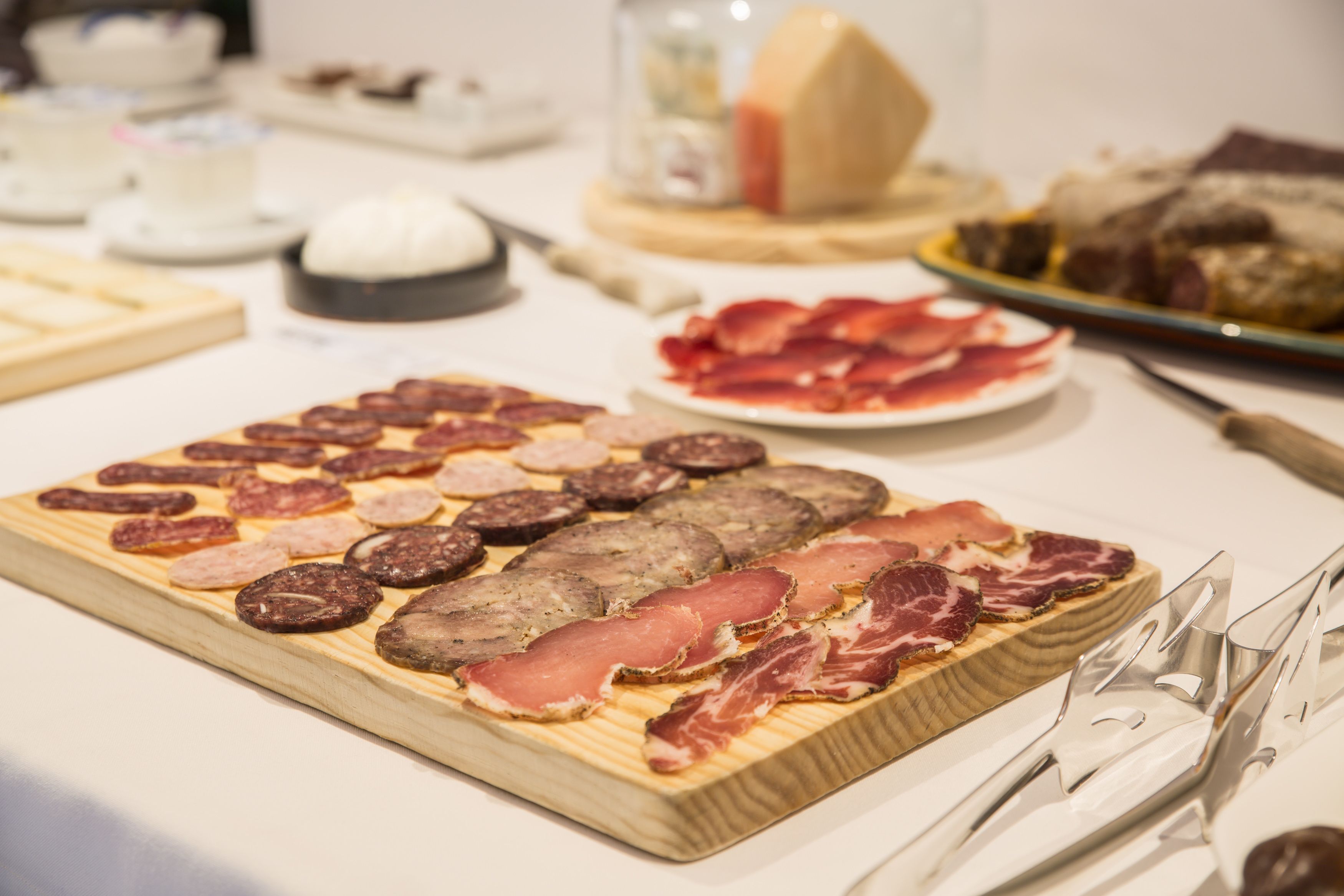 Une planche en bois sur laquelle sont disposés différents types de charcuteries et de fromages.
