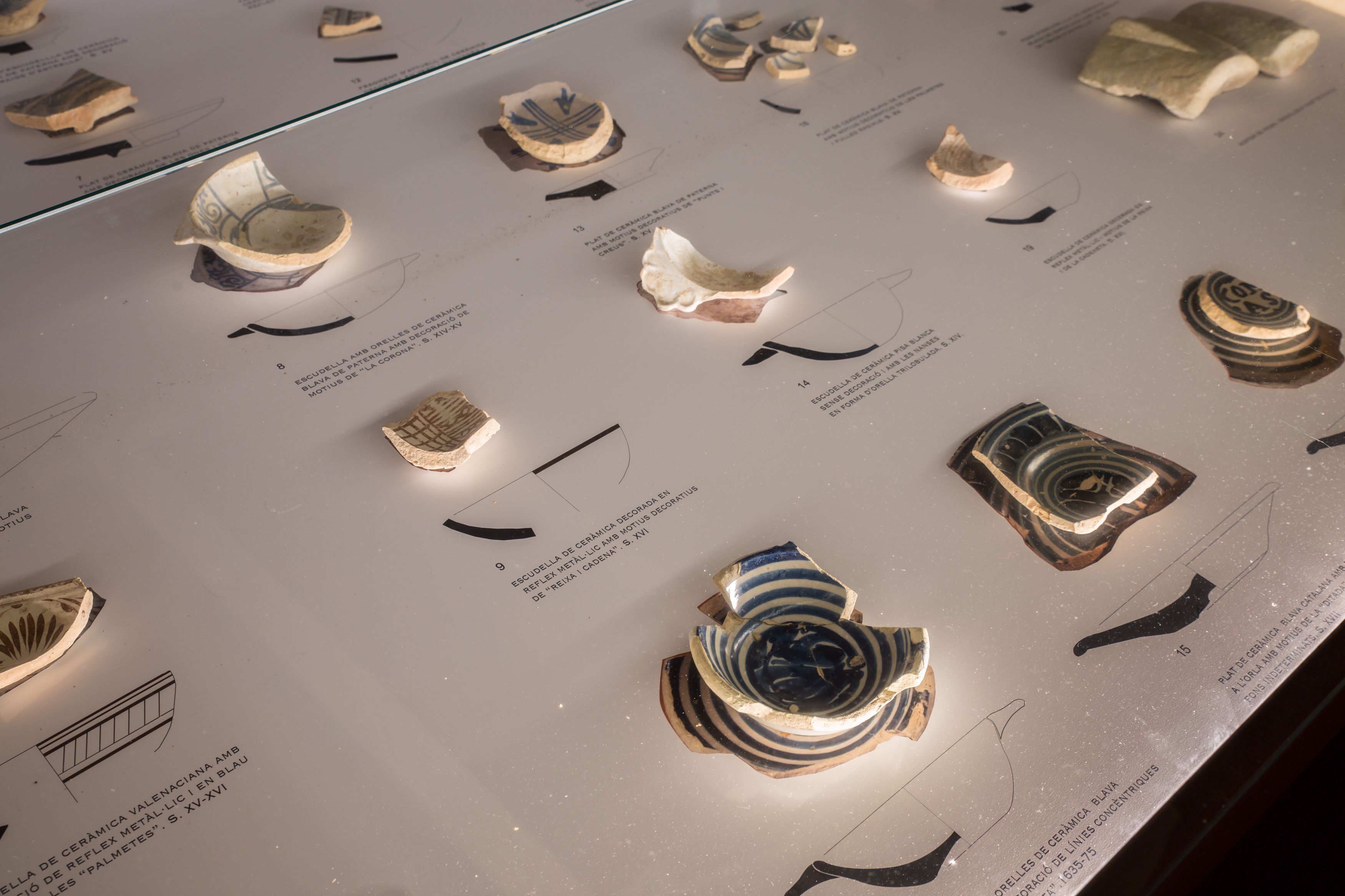 Una exhibición de piezas de cerámica con etiquetas y descripciones.