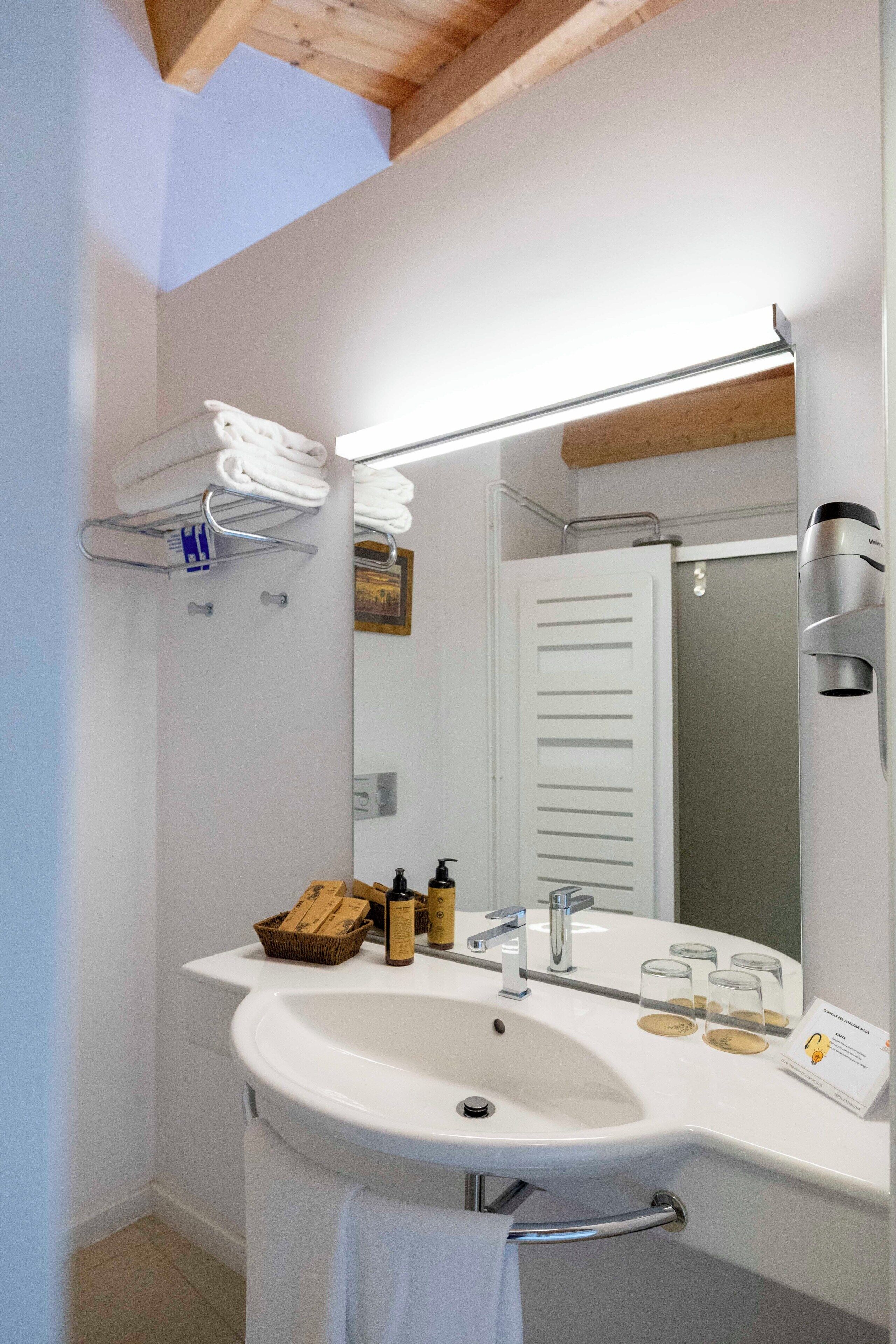 Une salle de bain moderne avec un lavabo blanc, un miroir et un porte-serviettes.