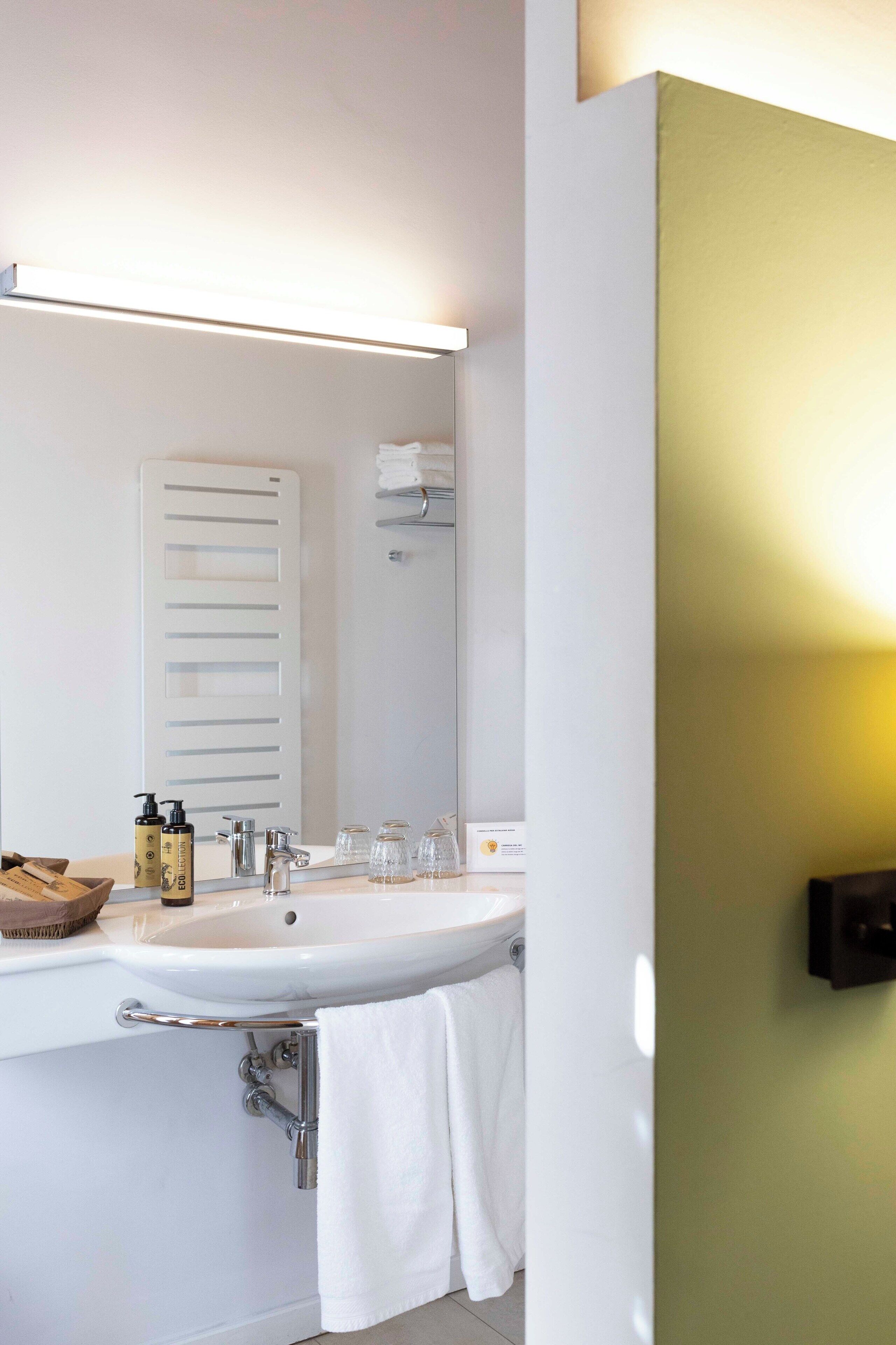 A bathroom with a large mirror, a sink, and a towel rack.
