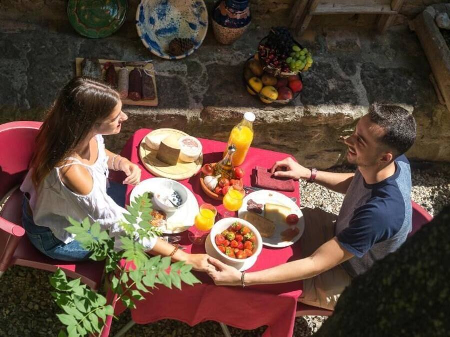 A dining table with a red tablecloth, surrounded by chairs, and a variety of food items and drinks.