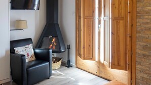 Un salon moderne avec une cheminée, un canapé en cuir noir et une porte en bois.
