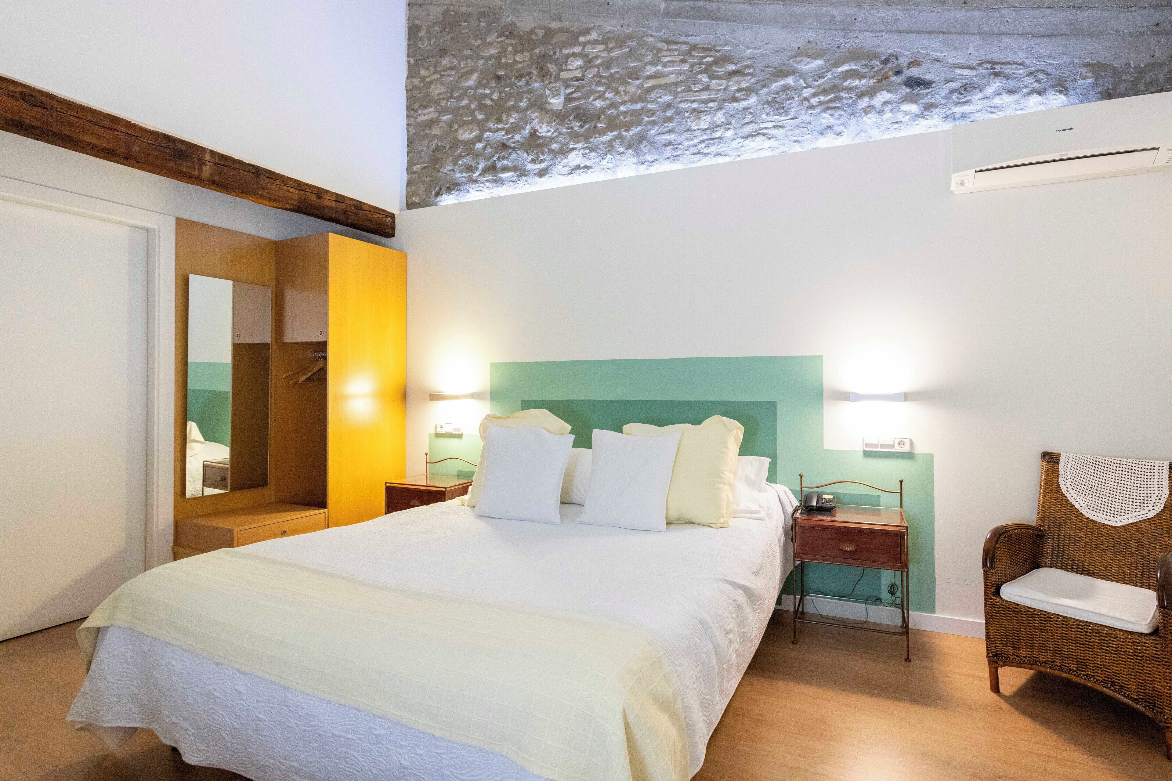 A bedroom with a bed, bedside tables, a chair, and a mirror.