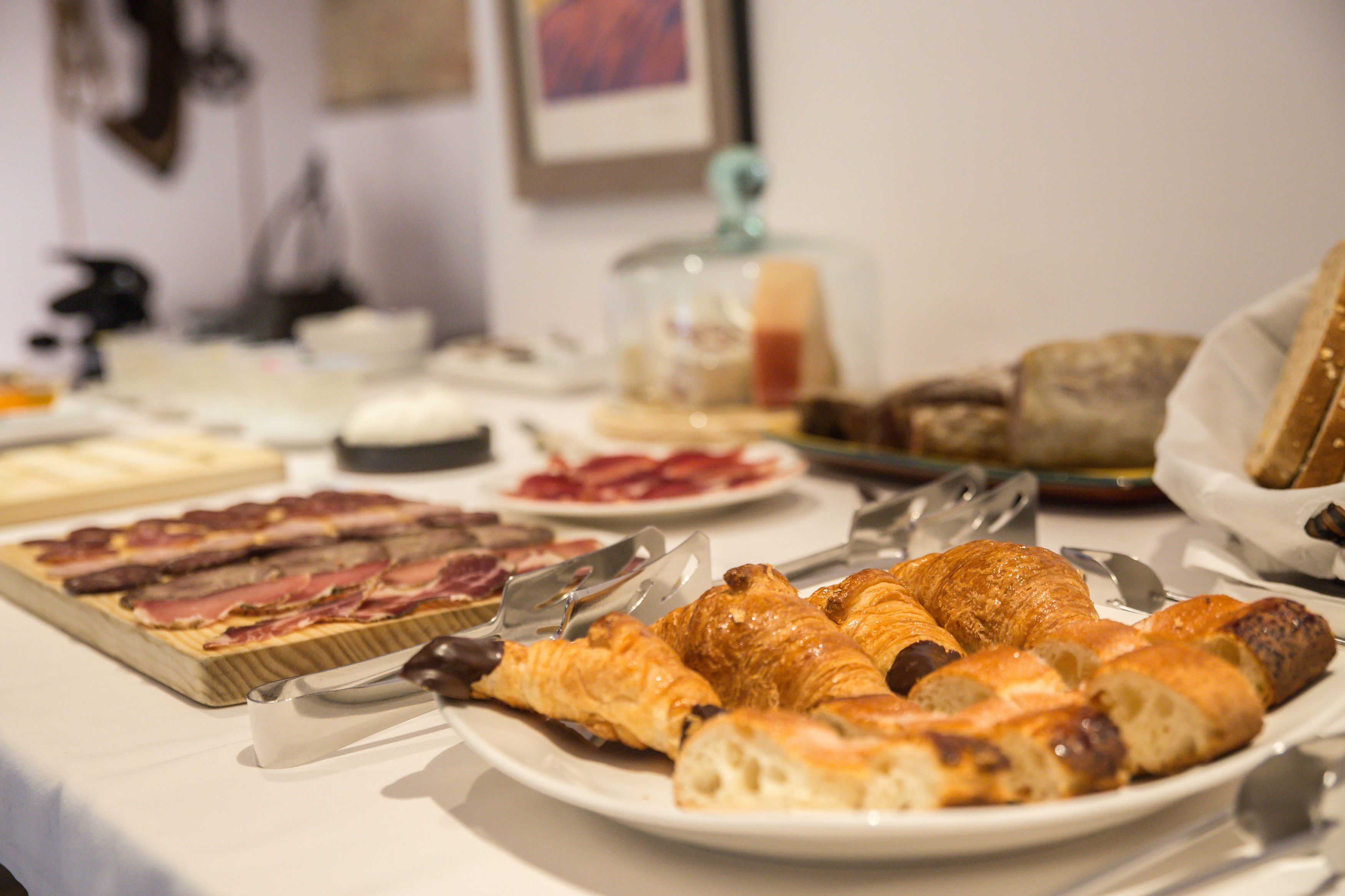 A breakfast buffet with various pastries, meats, and cheeses.