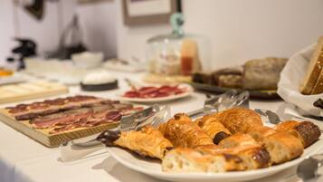 A breakfast buffet with various pastries, meats, and cheeses.