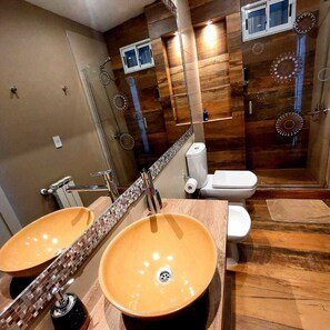 Une salle de bain avec deux lavabos, des toilettes et une douche.