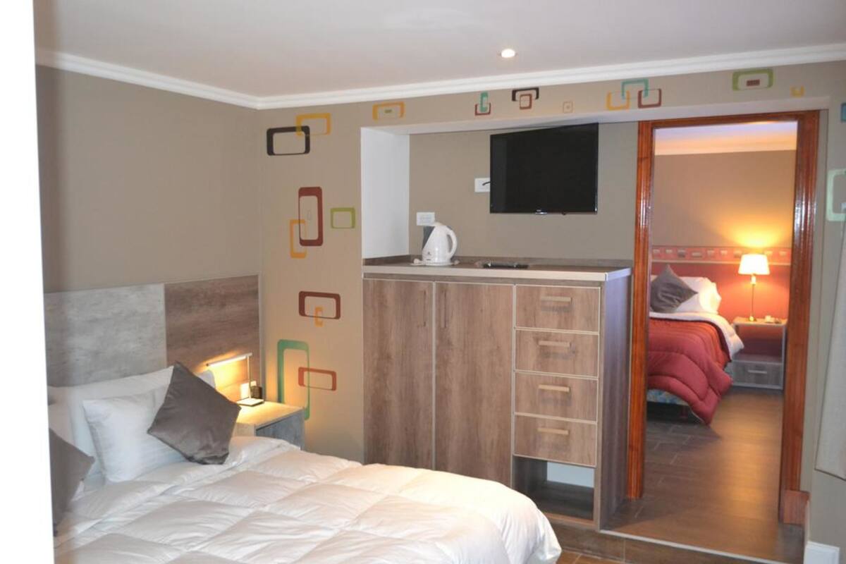 Una habitación de hotel con cama, escritorio, televisor y armario.