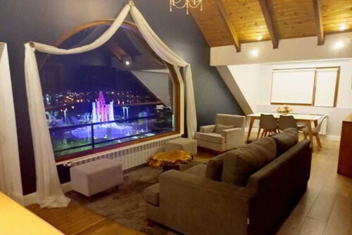 Un salón acogedor con un ventanal grande, un sofá y una zona de comedor.