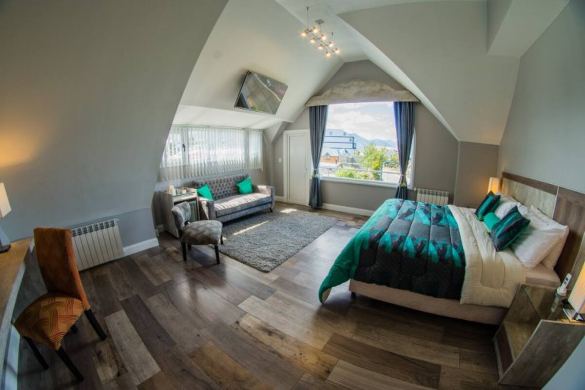 Un dormitorio con una cama grande, un sofá, una silla y una ventana con vistas.