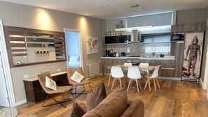 A modern living room with a sofa, dining area, kitchen, and a large window. -  Hostería y Restaurante América (Ushuaia)
