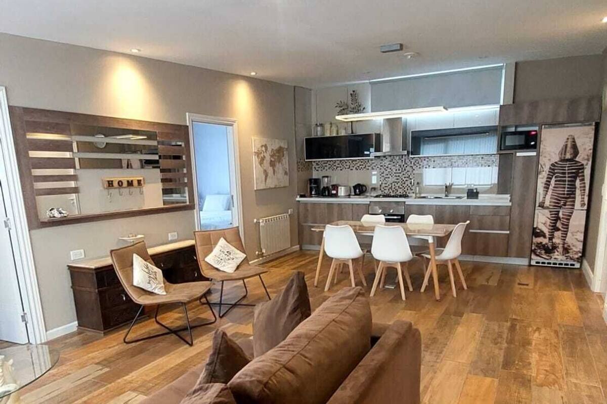 Una sala moderna con sofá, comedor, cocina y un ventanal grande.