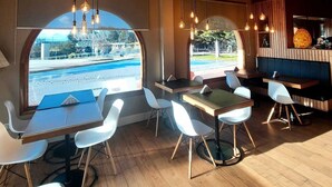 A restaurant interior with wooden ceilings, arched windows, and modern seating. -  Hostería y Restaurante América (Ushuaia)