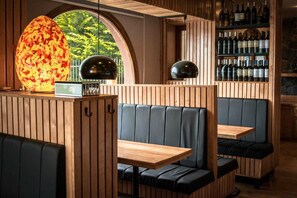 L’intérieur d’un restaurant avec des lambris en bois, des banquettes noires rembourrées et un meuble à vin.
