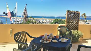 Enjoy a romantic meal for two on this marina-view terrace with a table set amidst a serene beach and sea backdrop.