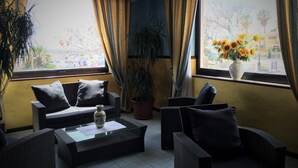 Una habitación con muebles de mimbre, un jarrón con flores y cortinas.