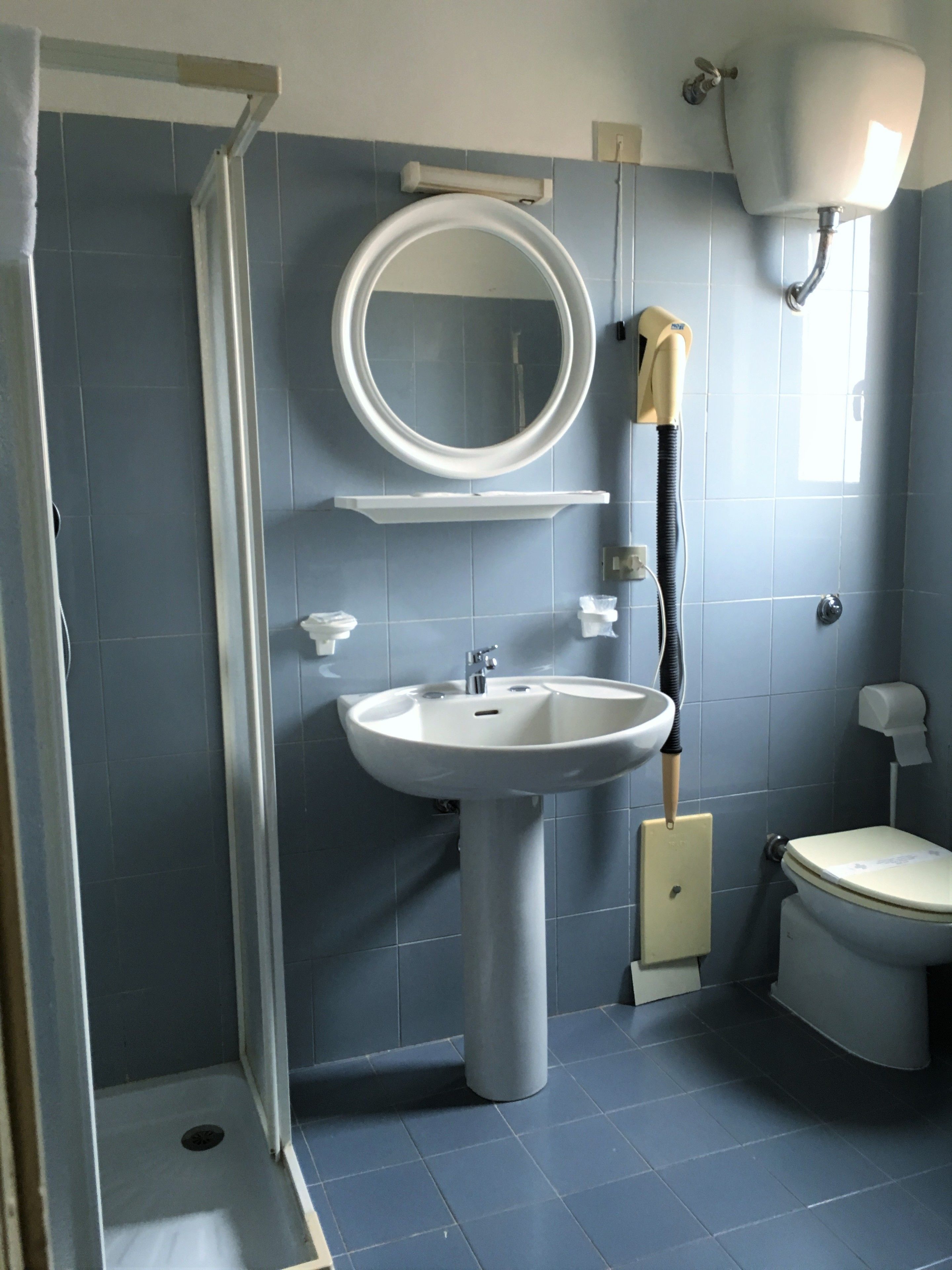 Ein Badezimmer mit Waschbecken, Spiegel, Toilette und Dusche.