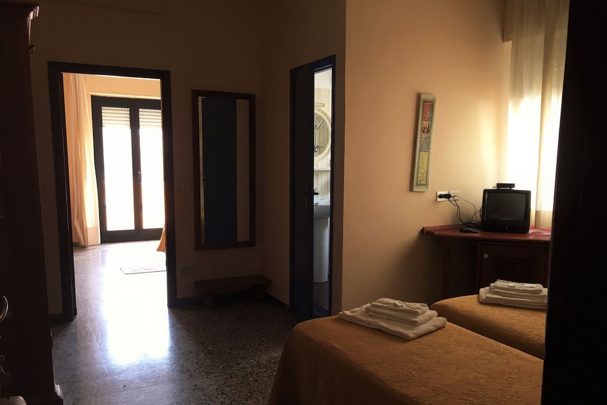 A hotel room with two beds, a television, and a bathroom visible through an open door.