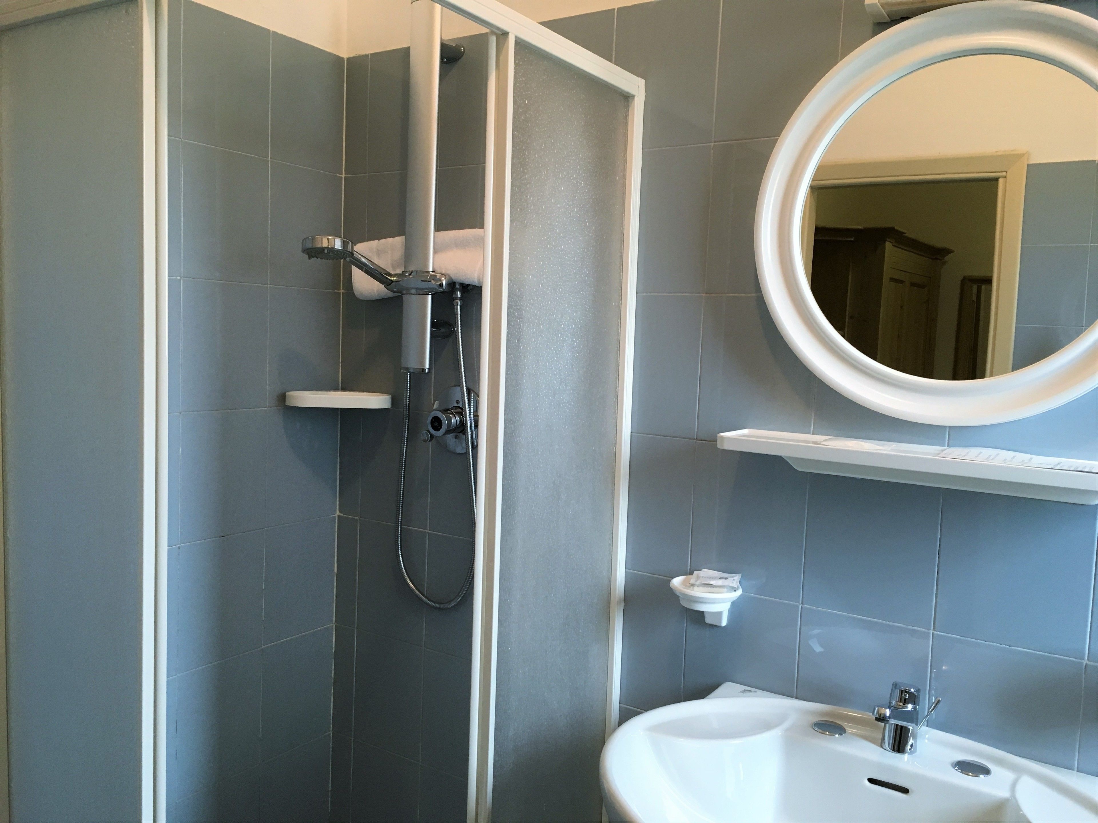 A bathroom with a shower, sink, and mirror.
