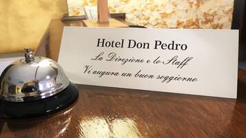 A hotel reception desk with a sign reading "Hotel Don Pedro" and a bell.