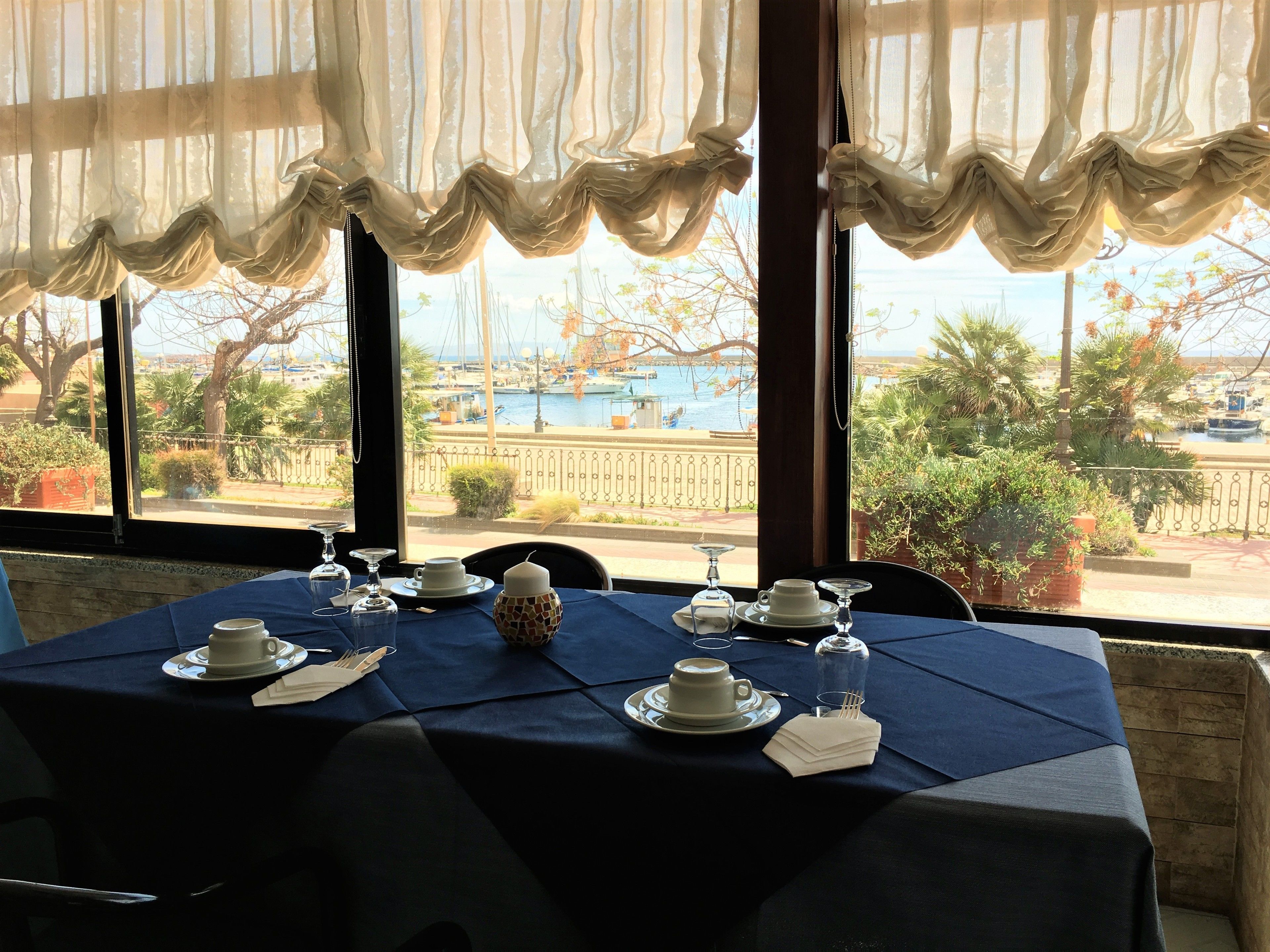 A table set for dining with a view of a marina and boats.