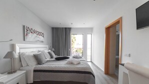 Een moderne slaapkamer met een bed, nachtkastjes, een lamp, een schilderij en uitzicht op het buiten.