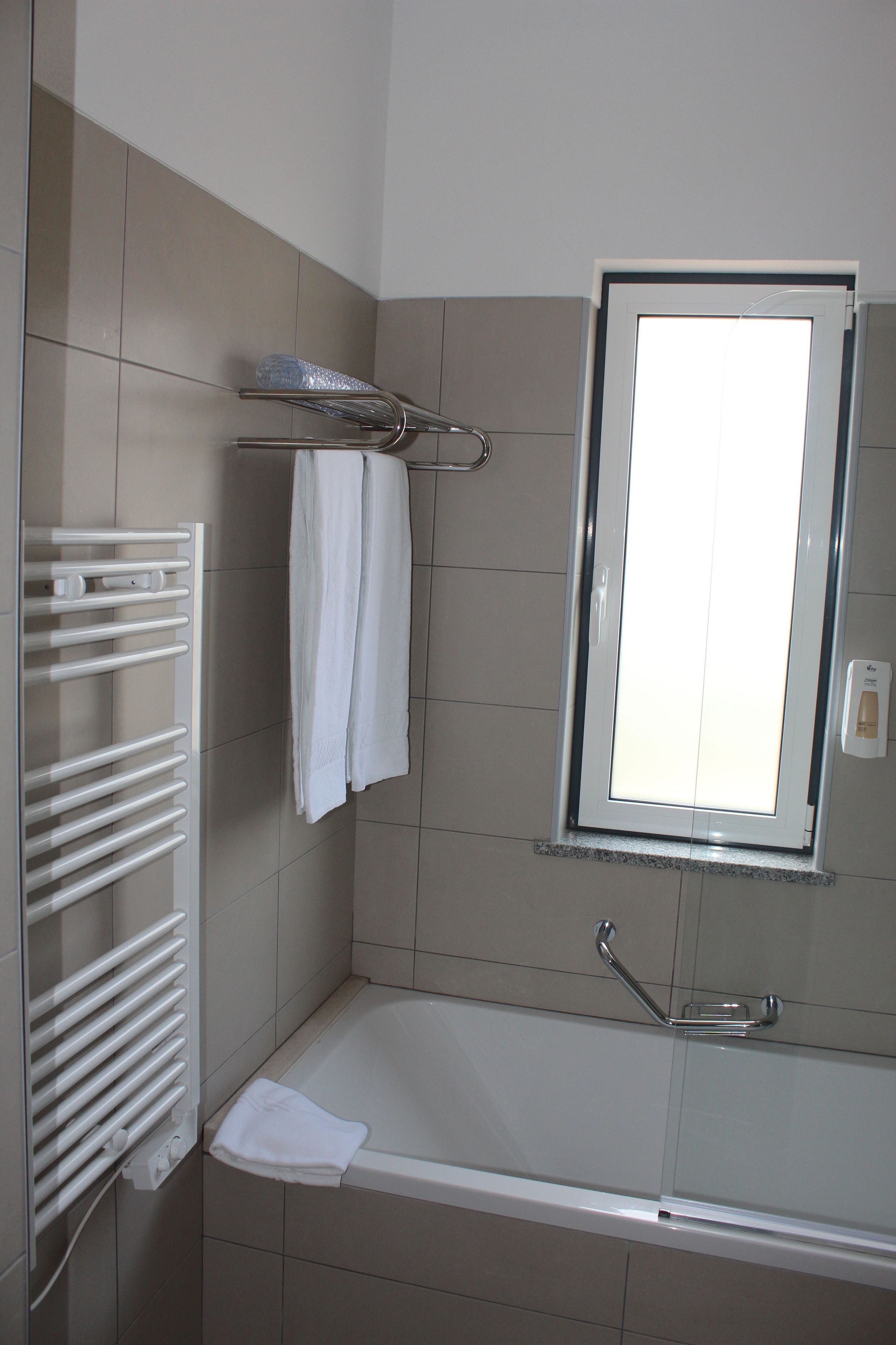 Une salle de bain avec une baignoire, un porte-serviettes et une fenêtre.