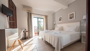 Een hotelkamer met twee bedden, een bureau, een stoel, een televisie en een raam met gordijnen.