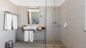 Une salle de bain moderne avec une douche à parois de verre, un lavabo et un miroir.