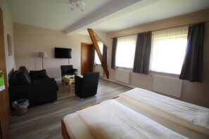 A hotel room with a bed, a sofa, a desk, and a TV.