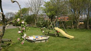 Children can play safely in this outdoor area with a swing set, slide, and sandbox.