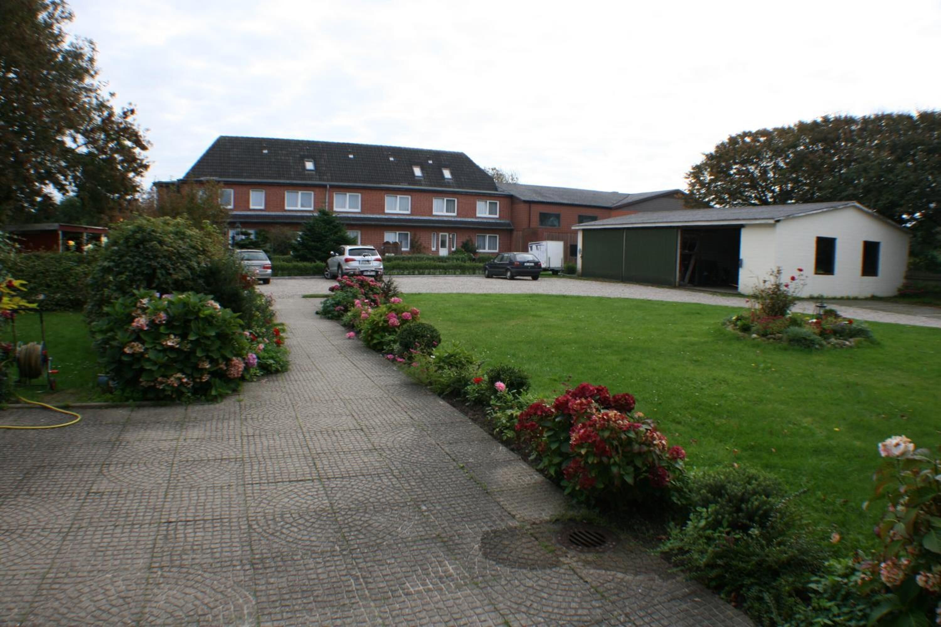 A residential area with a paved driveway, a lawn, and a small shed.