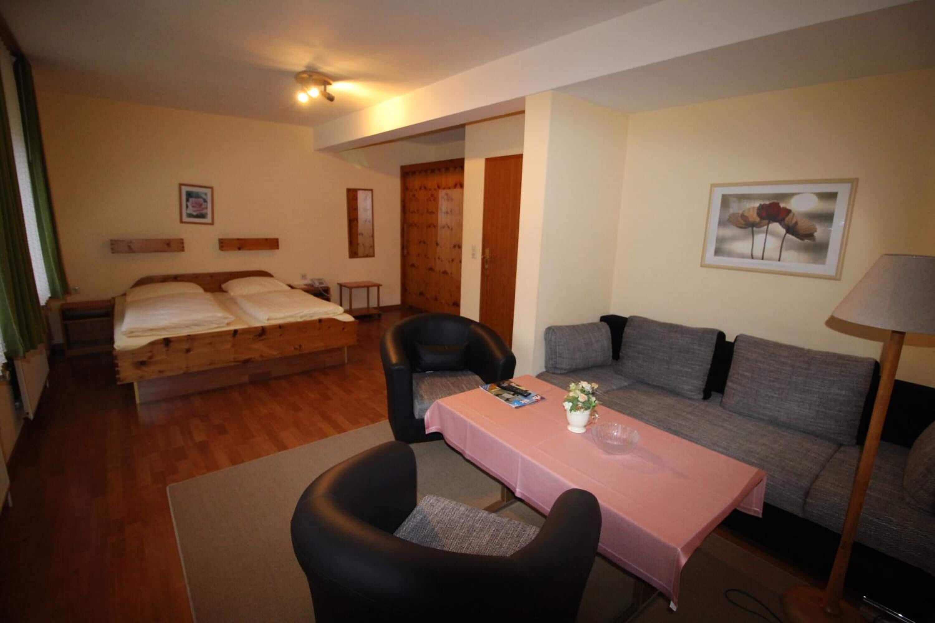 A hotel room with a bed, a sofa, a table, and a chair.