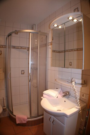 A bathroom with a glass-enclosed shower, a sink with a mirror, and a towel rack.