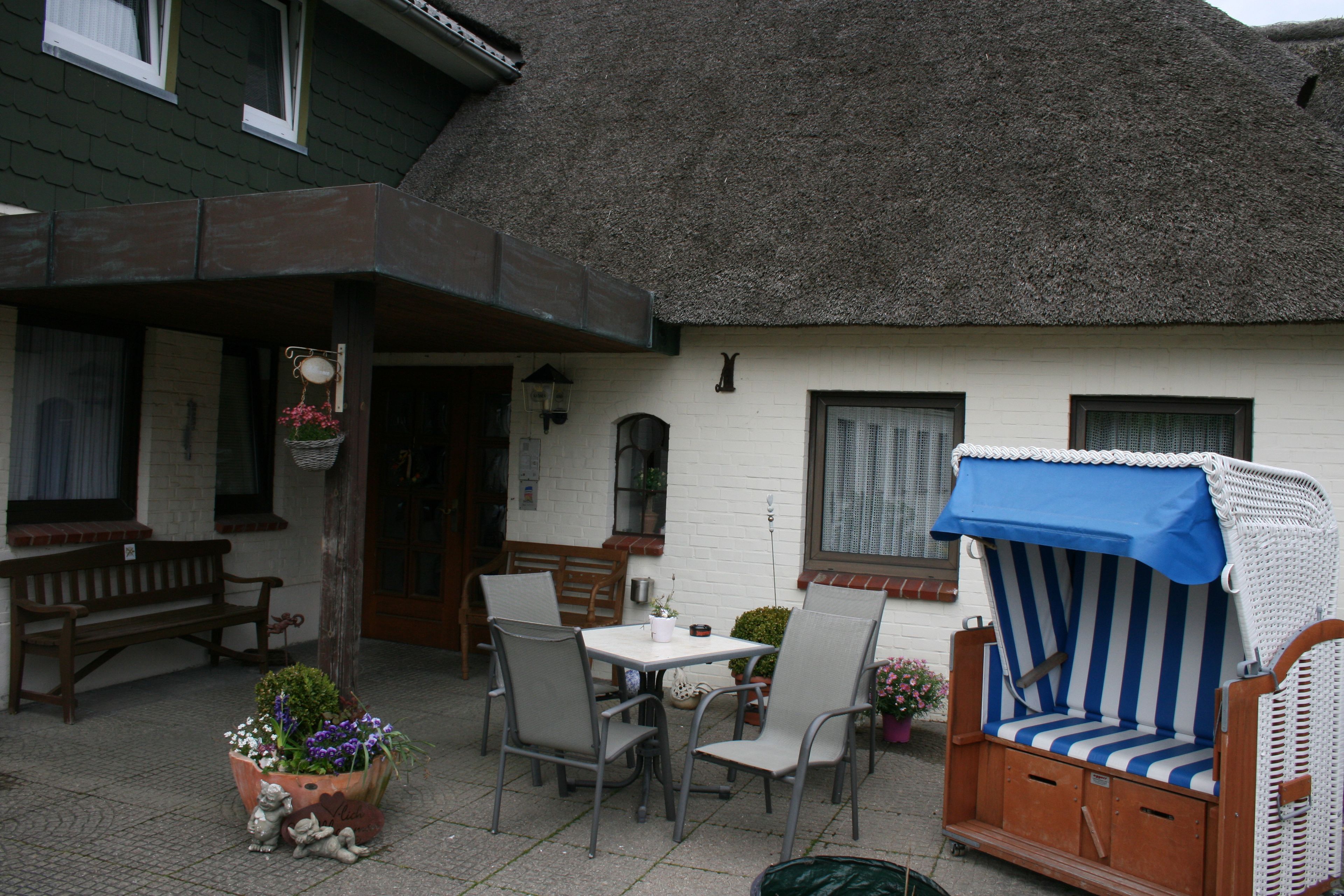 A patio with a table and chairs, a wicker chair, and a bench.