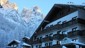 A hotel with multiple balconies, snow-covered surroundings, and a mountainous backdrop. - Nigritella (Selva di Cadore)