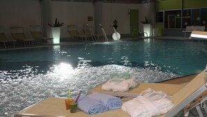 An indoor swimming pool with lounge chairs, towels, and a drink. - Nigritella (Selva di Cadore)