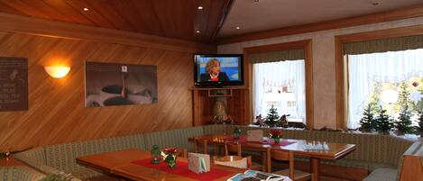 A cozy hotel lobby with wooden paneling, a television, seating areas, and a Christmas tree.