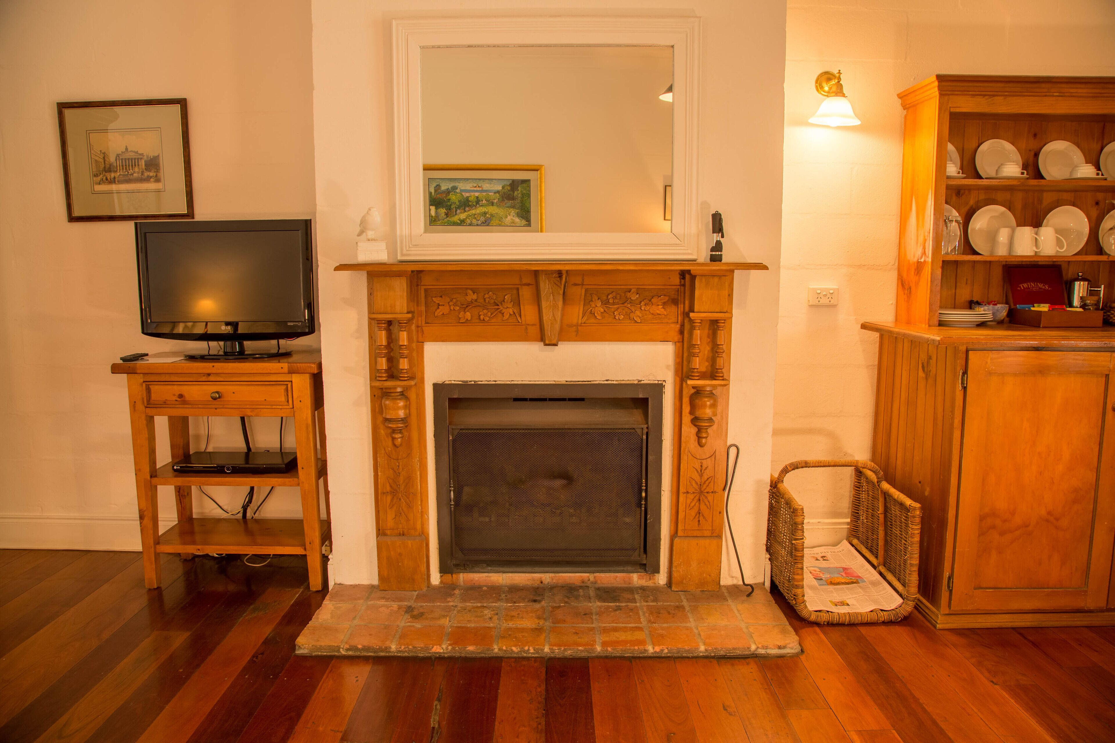 A living room with a fireplace, a television on a wooden stand, and a china cabinet.