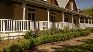 A traditional wooden house with a porch and white railings. - The Carriages (Pokolbin)