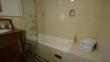 A bathroom with a glass-enclosed shower, a white bathtub, and a wooden vanity with a sink.